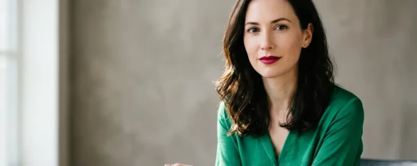 Portrait élégant d'une femme à la peau très claire portant un rouge à lèvres vif, mise en valeur par des tons chauds et froids harmonieux